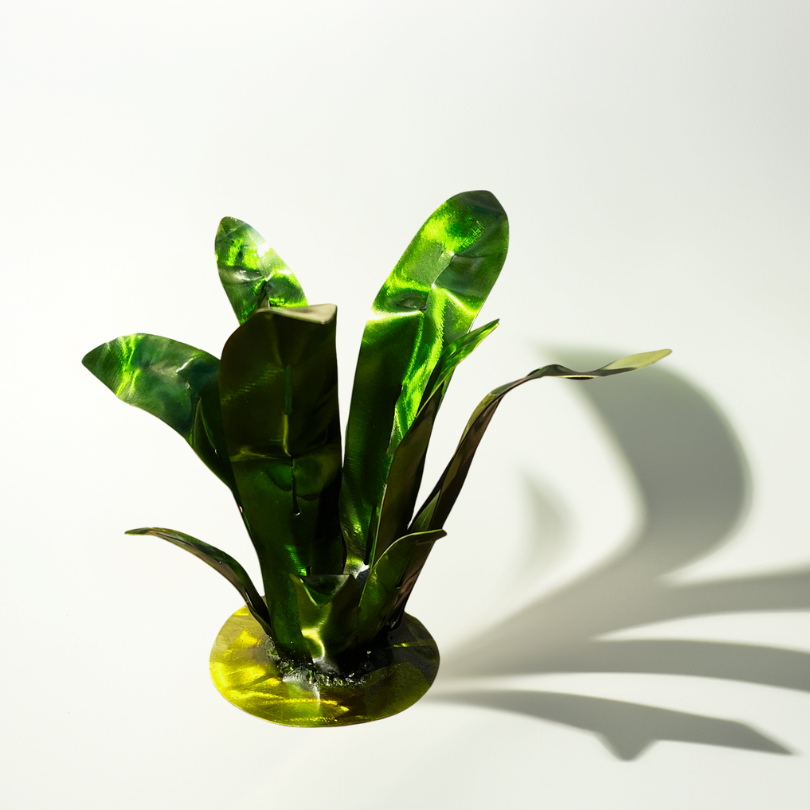 Spiky Desert Plant made of metal, displayed on a blank background and a funky abstract shadow is displayed to the right. Metal art plant has an airbrush painted finish of green and a hint of yellow on the leaves, a yellow base. A round welded base holds the agave plant shape. Vibrant and funky metal art for the garden or outdoor spaces or indoor. Fake metal plant that glimmers with sunlight or natural light.
