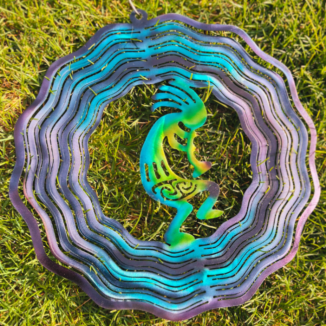Desert Art, Kokopelli is a mythical creature who makes music. He is a Trickster, musician, and helps with fertility. Metal Art wind spinner kinetic motion with bright colors- green, yellow, blue, purple and navy. Kokopelli art for desert landscapes. Kokopelli is a mystical creature metal art wind spinner. Displayed with grass, with several rings that extend to create a 3d metal art wind spinner