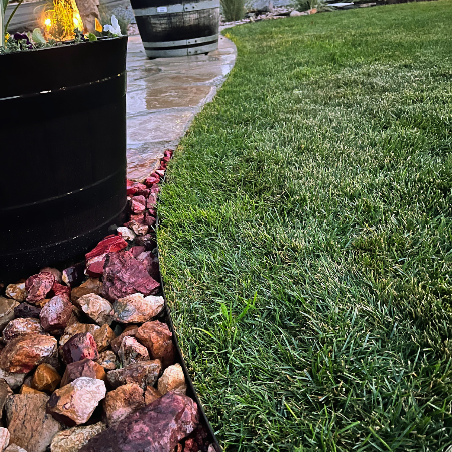 landscape scene with metal edging, rocks, healthy green grass, and planter pots