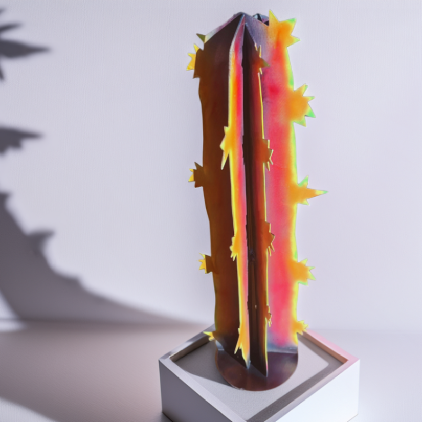 Vibrant and colorful metal cactus art, cut from steel and welded together, painted with neon colors- light green, yellow, purple, pink and orange. standing on a box, displaying a shadow on the wall. Cactus is cylindrical, tall and slender 